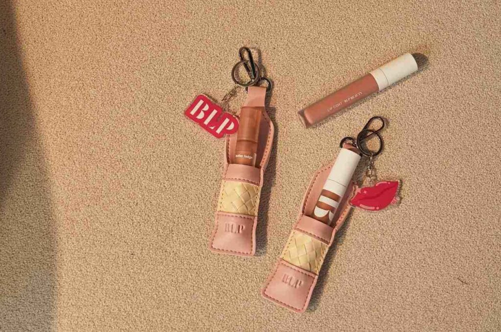 Produk kolaborasi BLP x Du Anyam berupa lipstick sleeve anyaman dengan key chain diletakkan diatas pasir