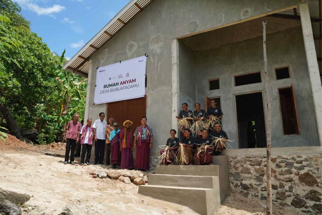 komunitas Du Anyam yang berdiri sambil tersenyum di depan rumah anyam Desa Bubuatagamu NTT sebagai tempat pusat kegiatan dan kolaborasi bersama